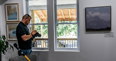 An inspector documenting a rental unit next to a bright window