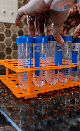 Gloved hands placing sample tubes into an orange rack