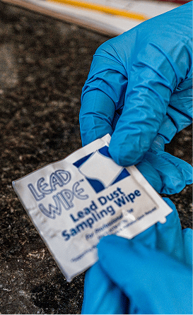 A gloved hand holding a Lead Wipe dust sampling wipe